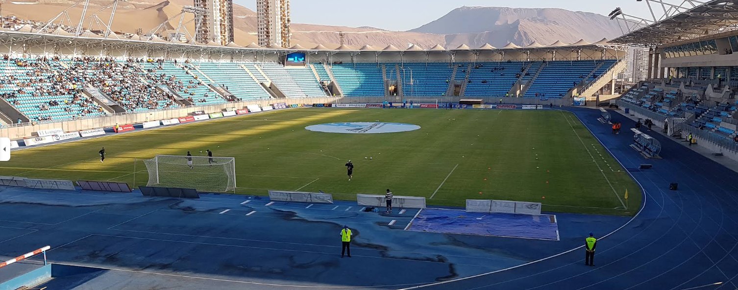 Vista del estadio Tierra de Campeones de Iquique previo a un partido, con el cerro y las dunas de fondo